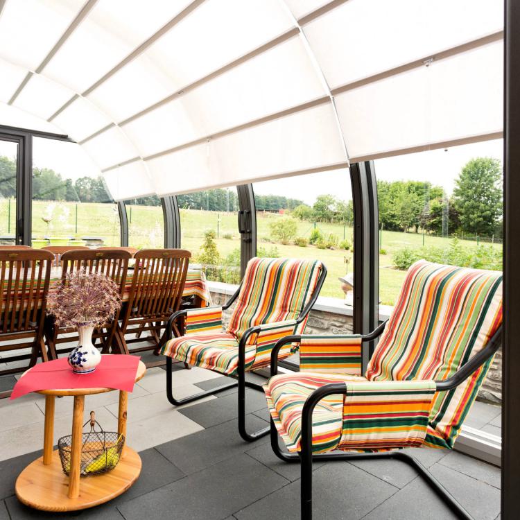 Abri de terrasse Saphir : vue de l'intérieur avec le strore de protection solaire baissé
										